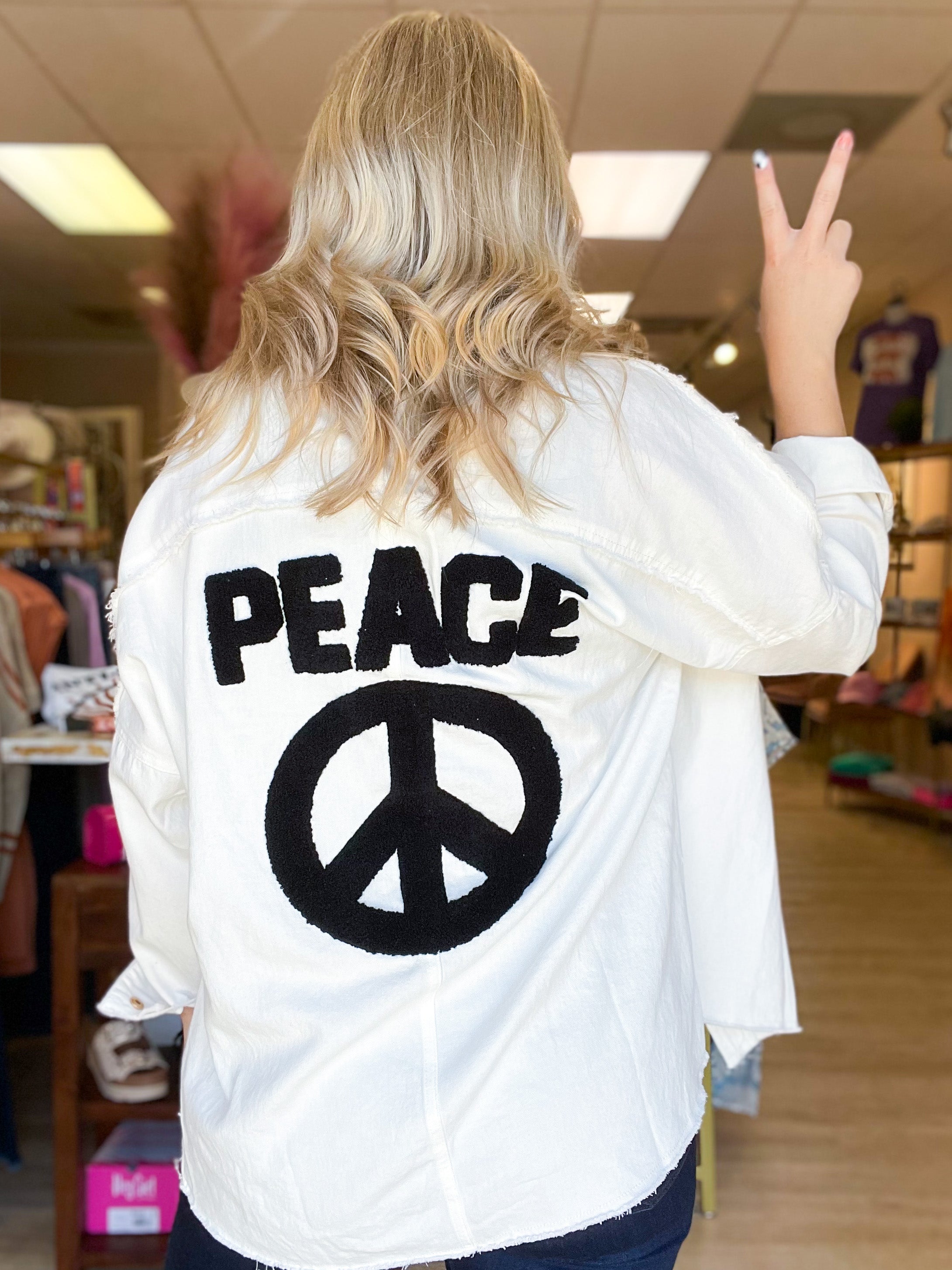 white denim jacket with black peace and peace sign on the back